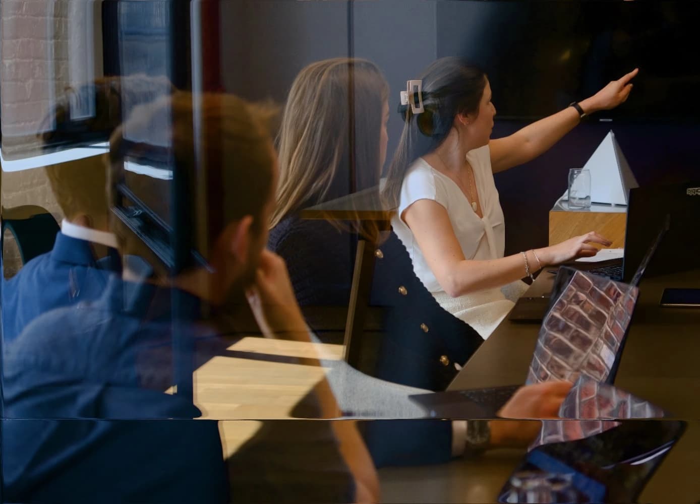 Hebbia team collaborating in a modern meeting room with laptops and strategic pointing gesture.